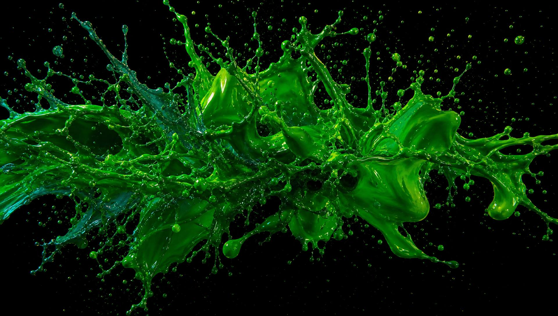 Vivid emerald green paint splash exploding against a black background